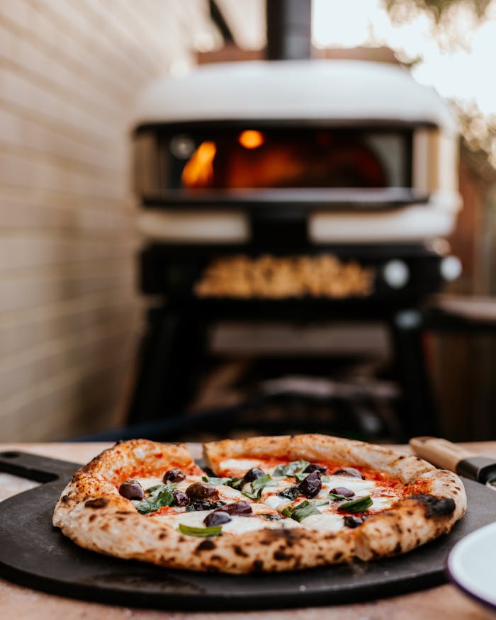 A mouth-watering pizza fresh from an outdoor oven, showcasing traditional Italian ingredients.